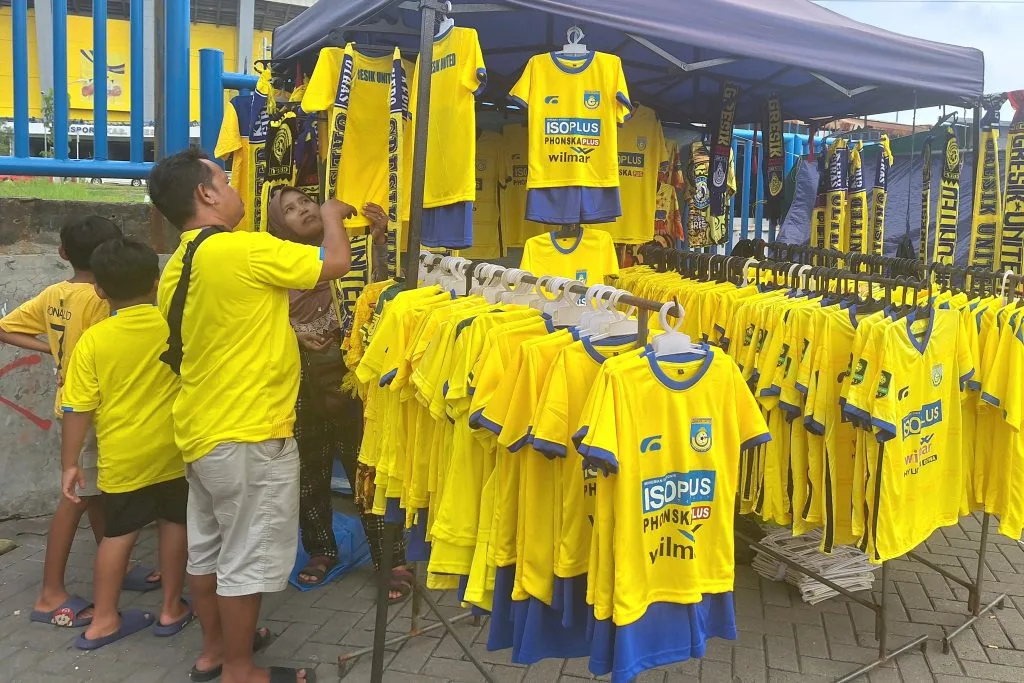 Pegadaian Liga 2 Beri Ruang UMKM Mendulang Berkah Foto : Bu Nanik saat kedatangan penonton dengan anaknya untuk membeli merchandise UMKM (c)iansetiawan