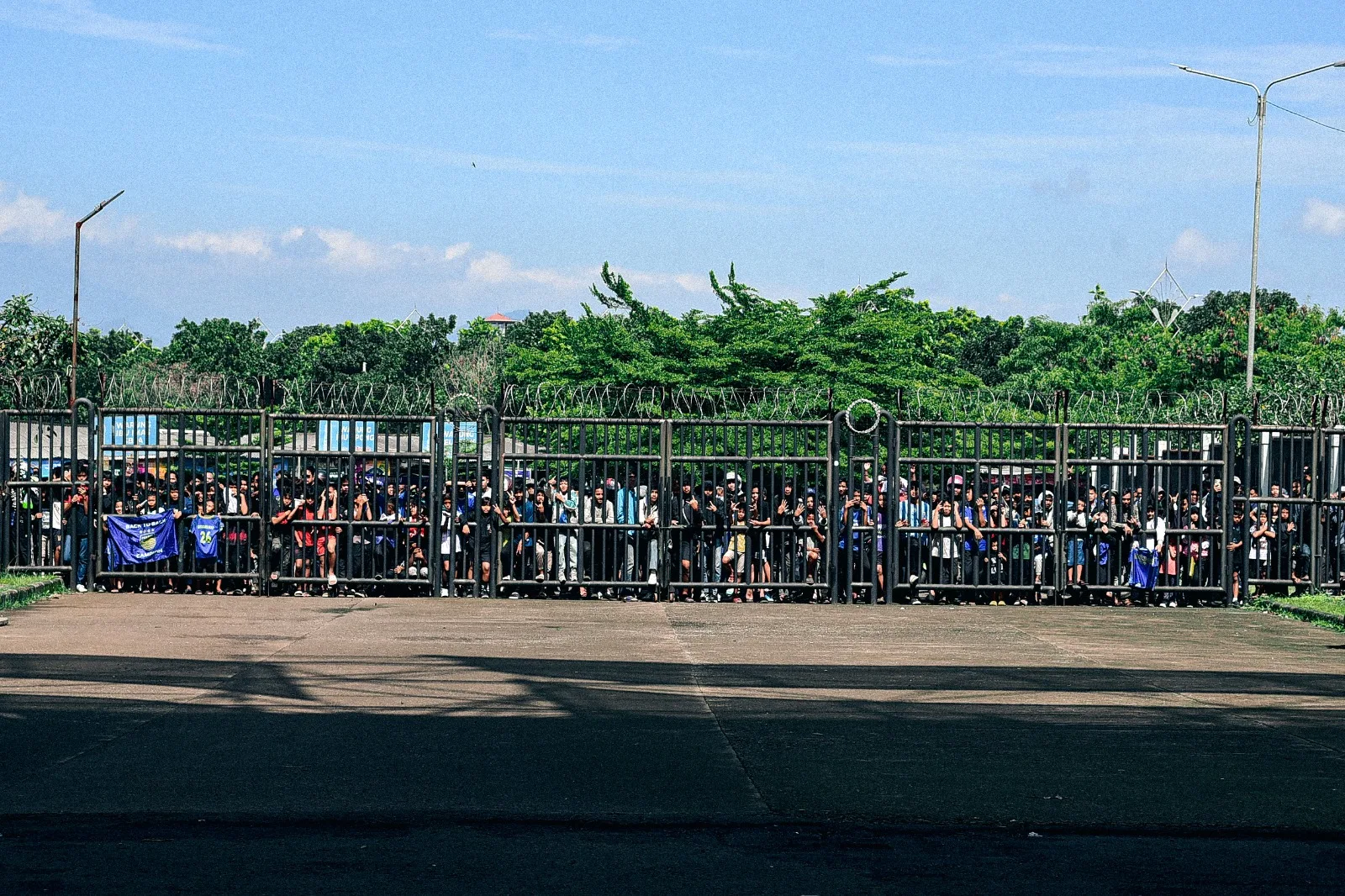 Para bobotoh menunggu para pemain persib bandung di depan gerbang merah merah Stadion Gelora Bandung Lautan Api, Kota bandung, senin (30:05-2025). (Foto- EgiSaeful:Totalsport.id) Moment Latihan Perdana Persib Bandung - Moment Latihan Perdana Persib Bandung Musim 2025/2026
